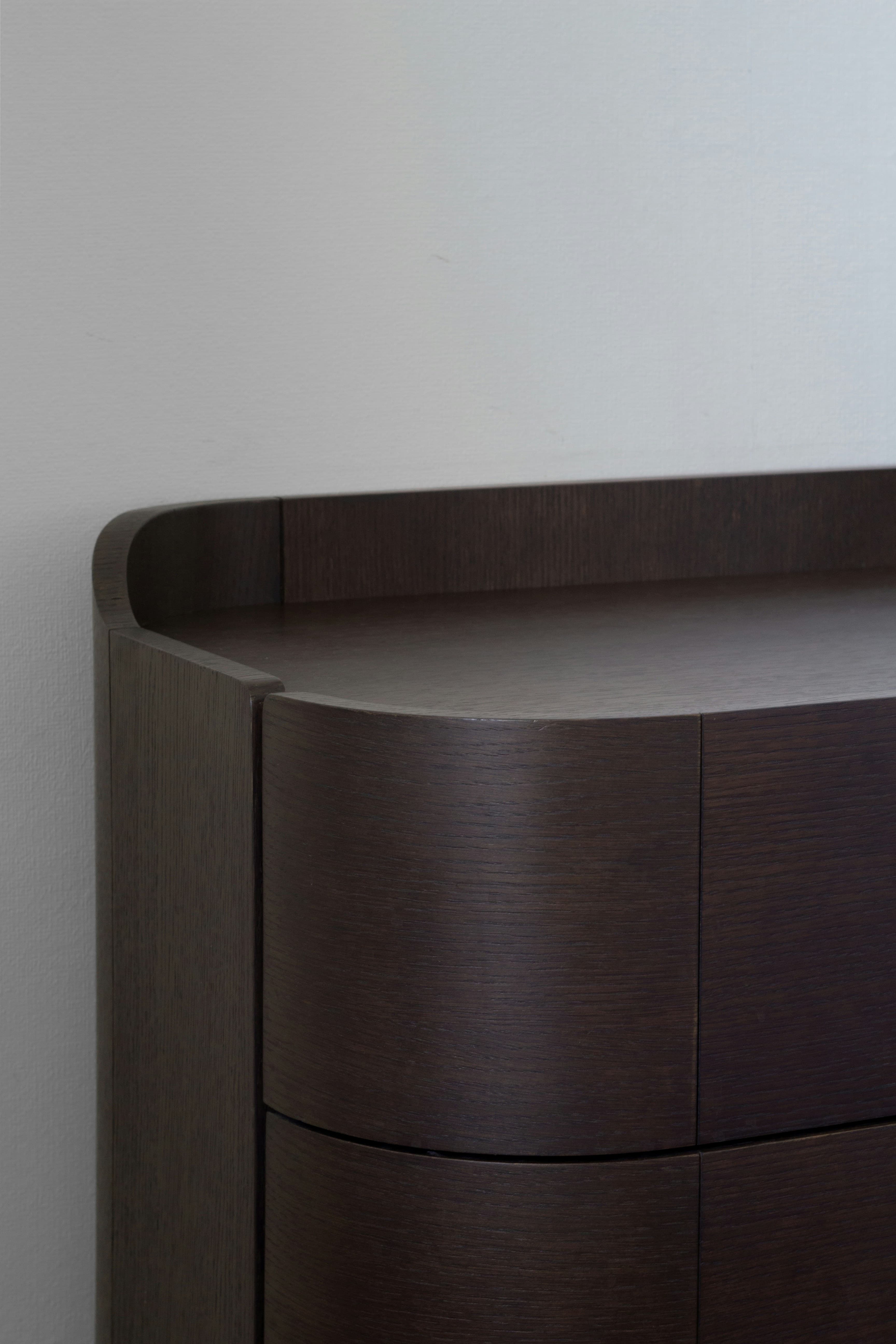 Close-up van een strak gewrapt, donker houtlook meubel met afgeronde hoek.