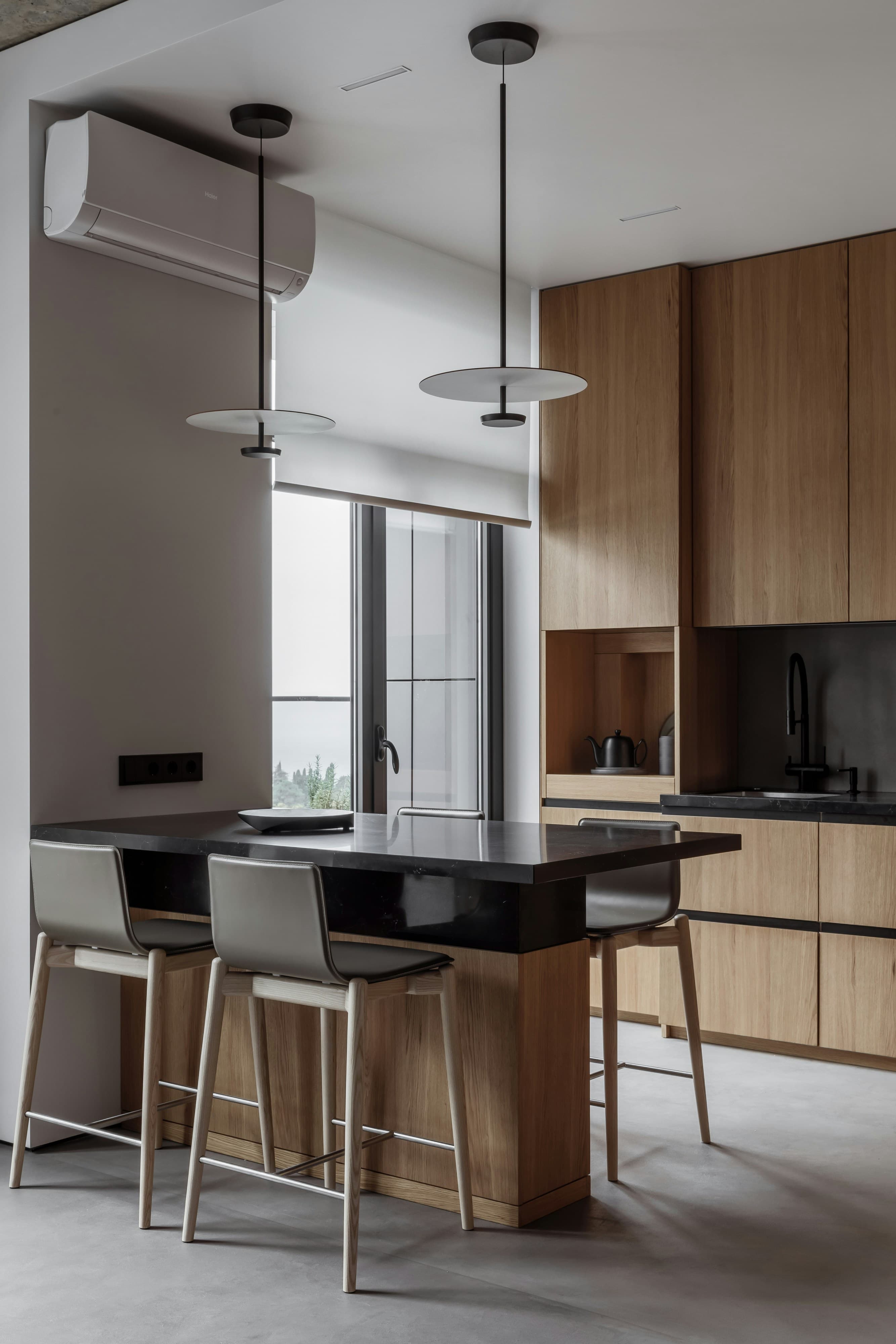Moderne kantoorpantry met houtlook fronten en zwart werkblad.