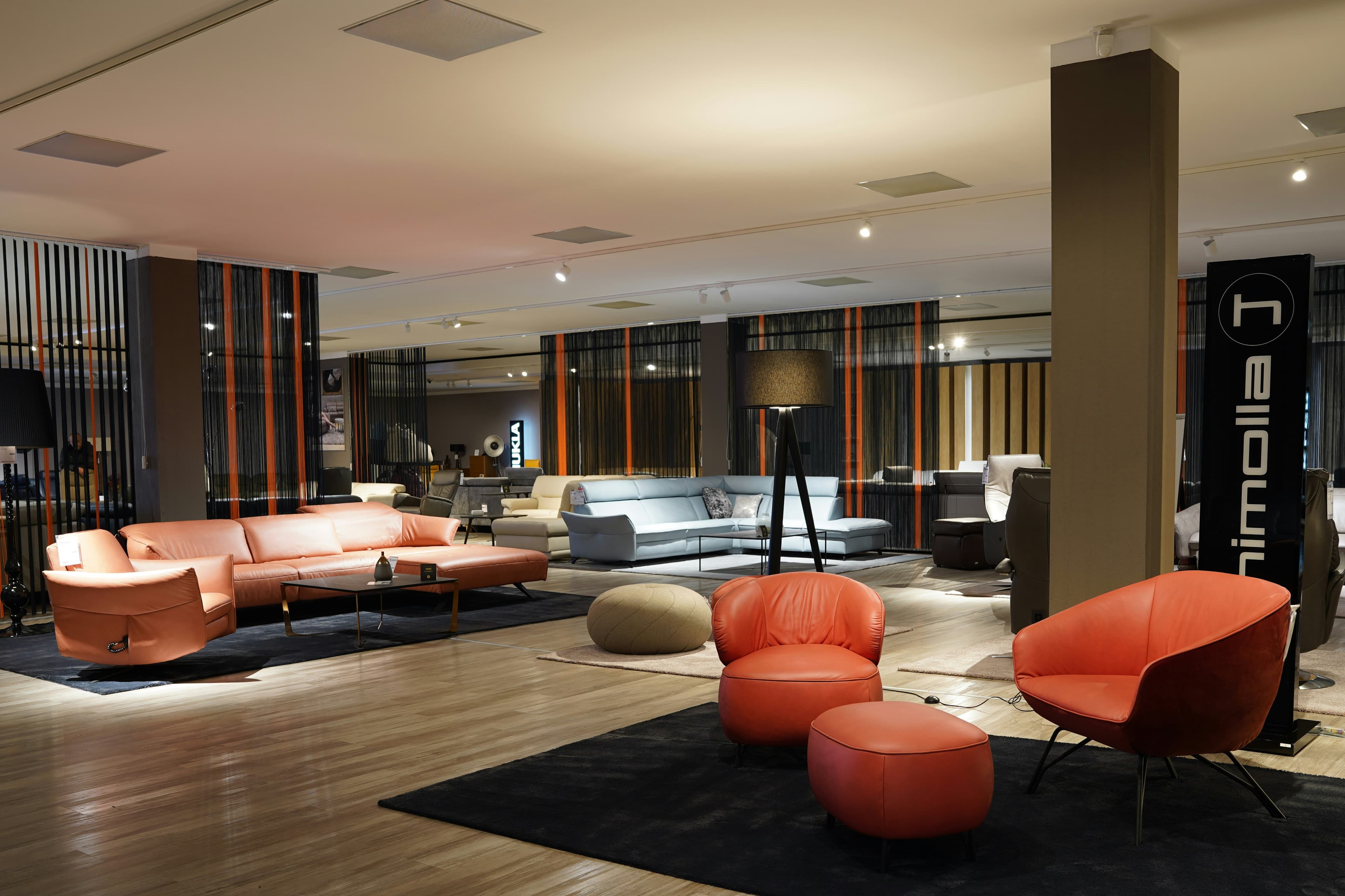 Ruime meubelshowroom met loungemeubels en sfeerverlichting.