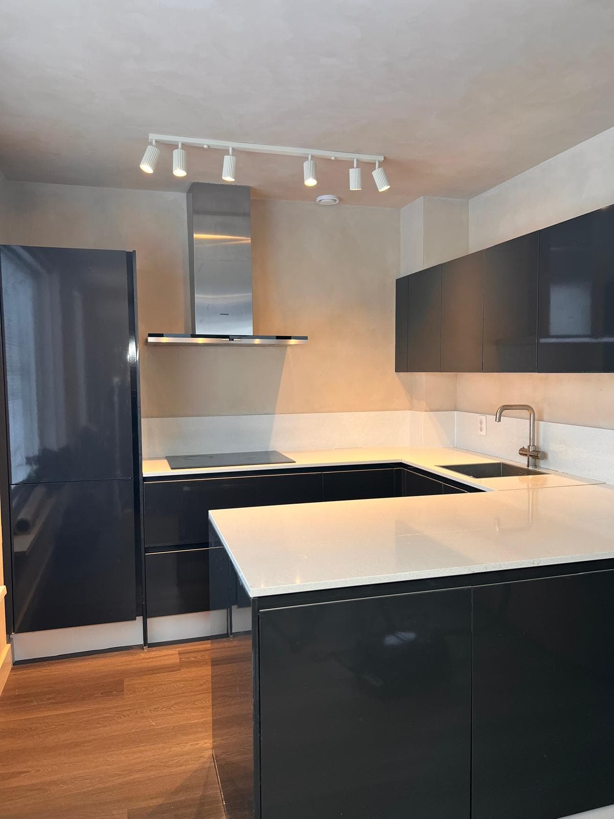 Mat zwarte keuken met wit werkblad en messing kraan