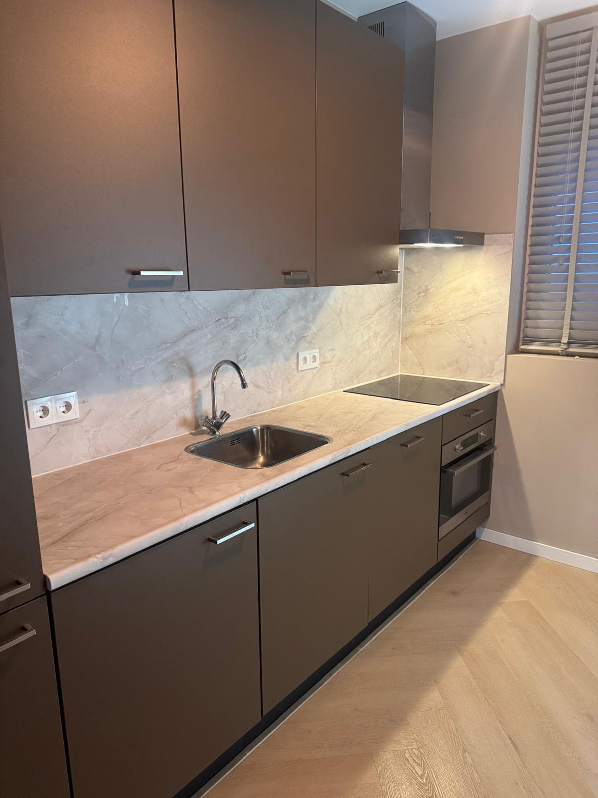 Taupe keuken met marmerlook wand en werkblad